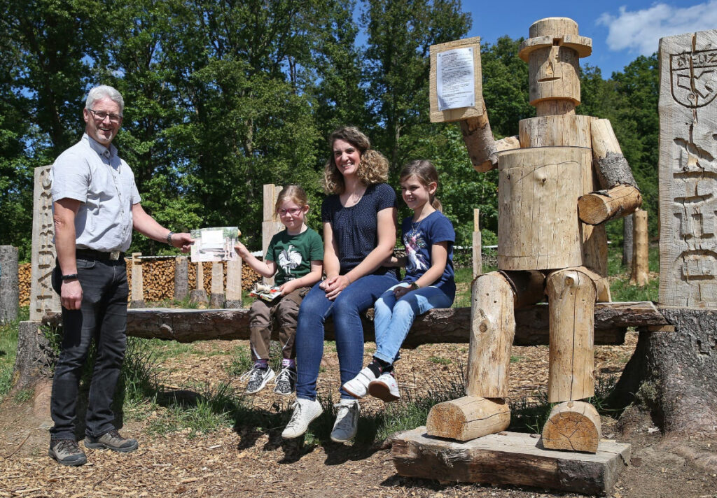 Menschen in Natur neben Holzwerken