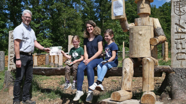 Menschen in Natur neben Holzwerken