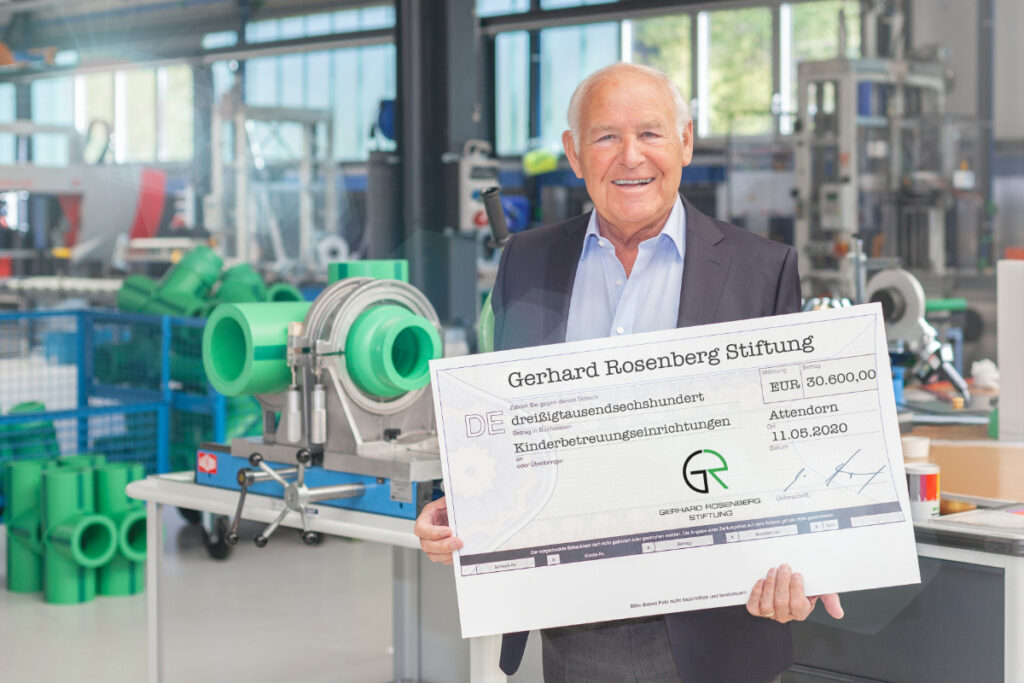 Mann mit Spendencheck vor Industriegelände