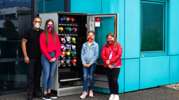 Vier Menschen vor Automat für Munschutzmasken