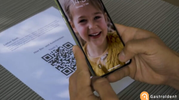 Handy mit Kinderbild, im Hintergrund Tisch mit QR-Code