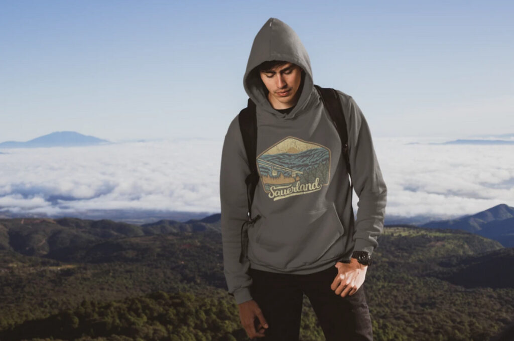 Mann mit Sauerland-Hoodie vor bergiger Landschaft