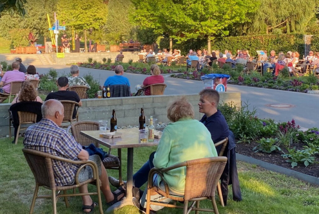 Menschen an Tischen in grüner Umgebung