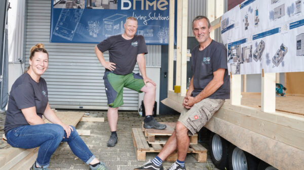 Leute sitzen bei der Arbeit, nebenan Tiny House