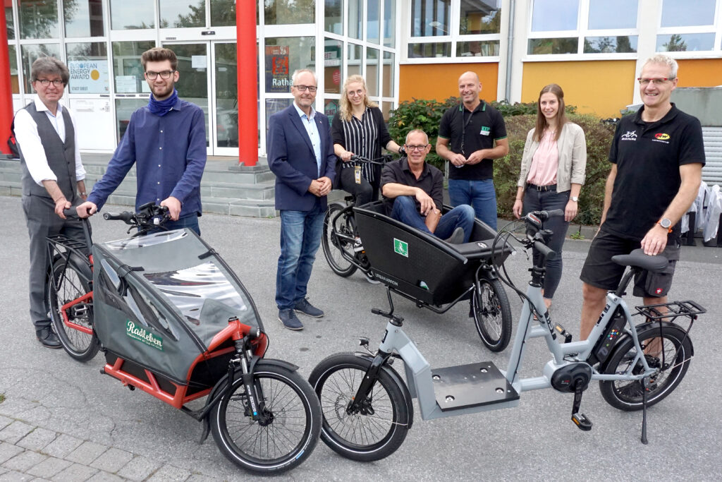 Menschen stehen mit Lastenrädern vor einem Gebäude