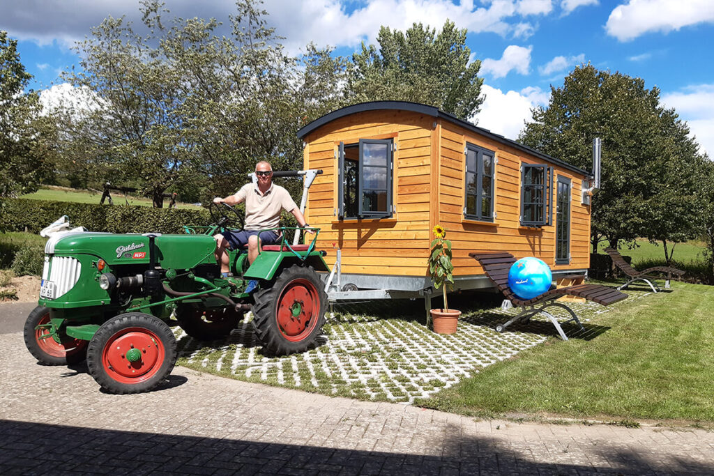 Mann auf Traktor zieht Holzwagen