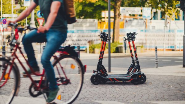 Ein Mann fährt auf einem Fahrrad. Im Hintergrund stehen E-Scooter