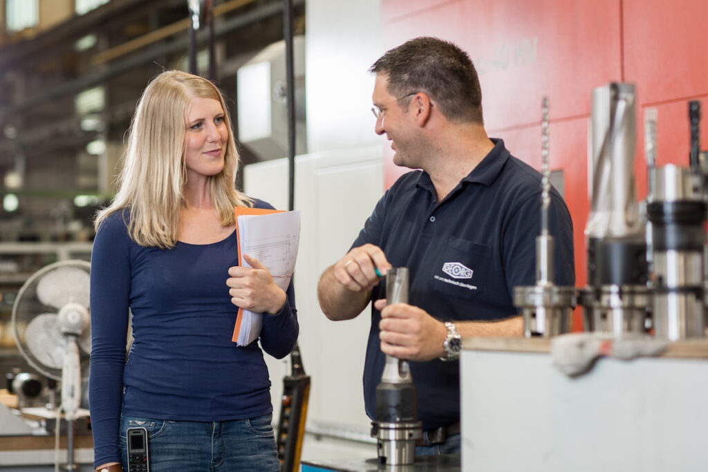 Eine Frau und ein Mann unterhalten sich in einer Fabrik