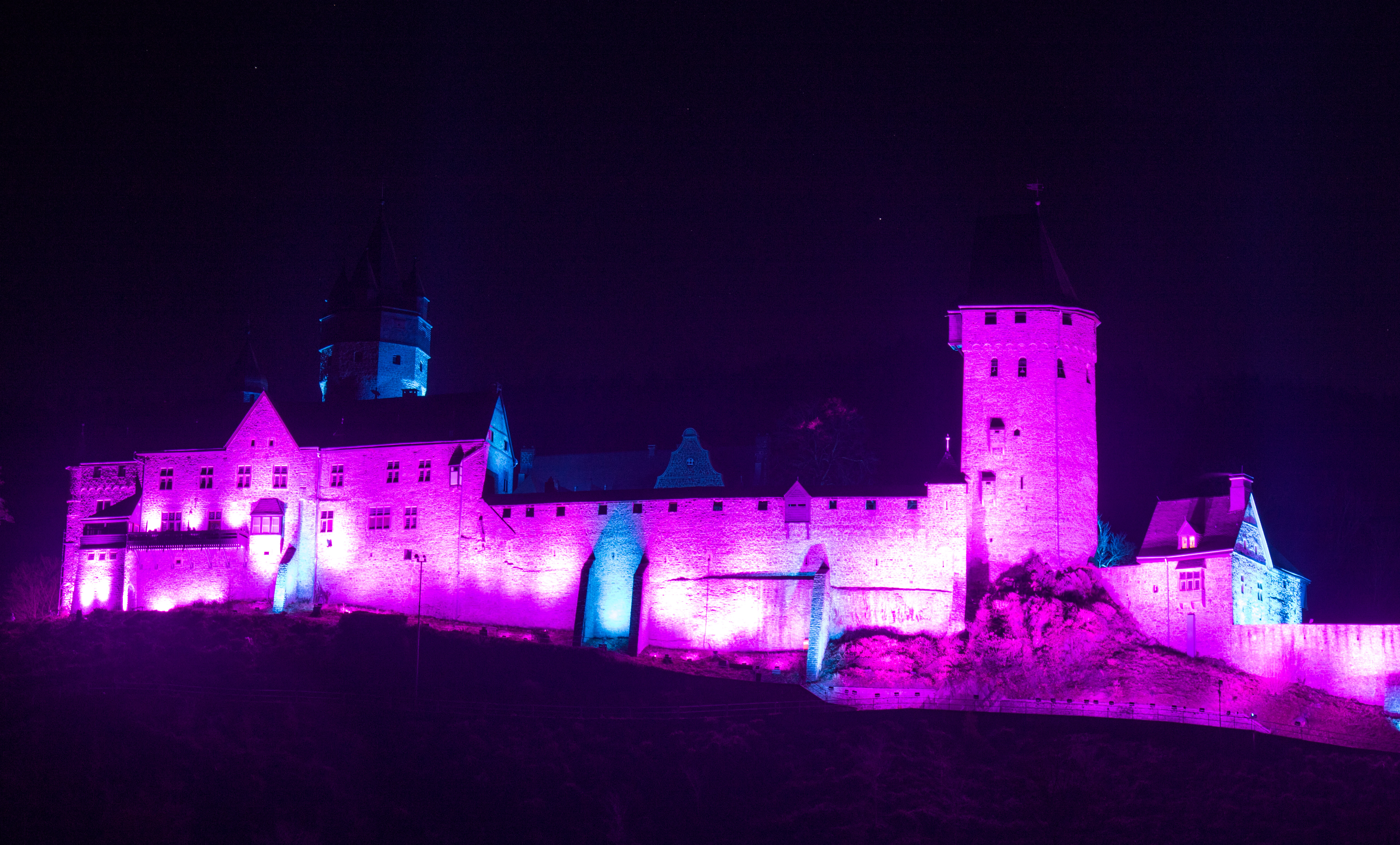 Eine Burg wird mit lila Beleuchtung angestrahlt
