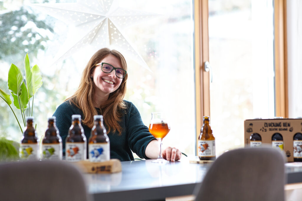 Frau mit Bier sitzt am Tisch