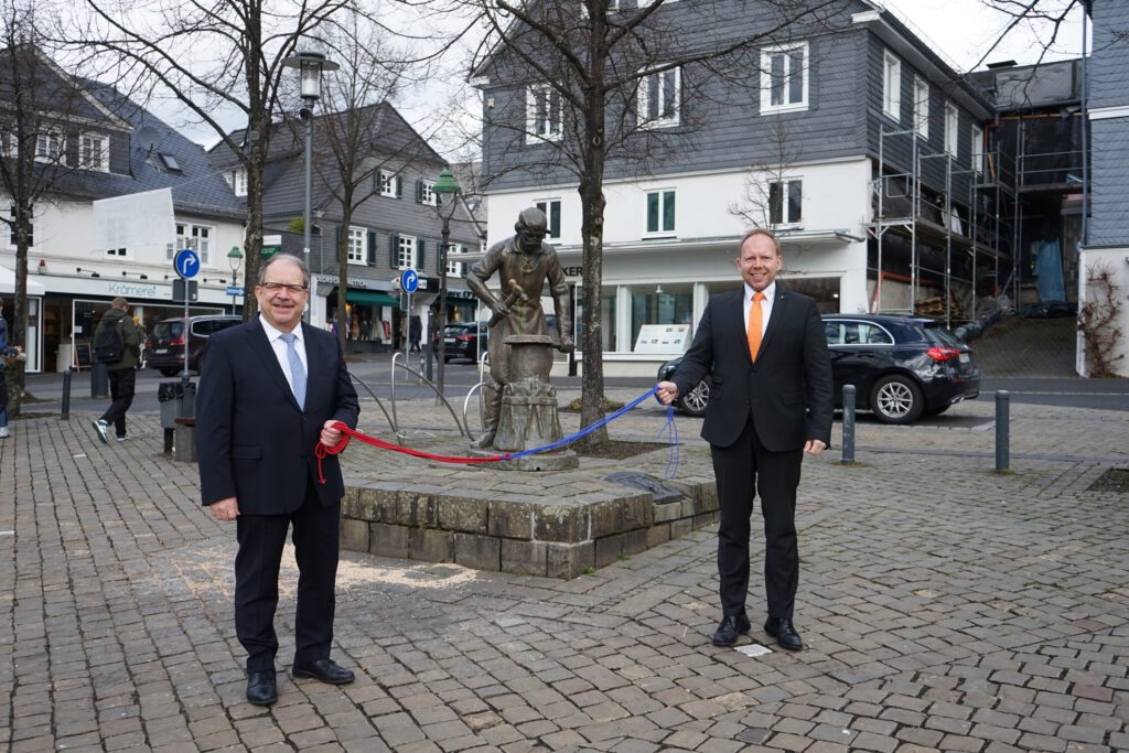 Zwei Männer stehen auf dem Olper Marktplatz und halten ein Seil in den Händen