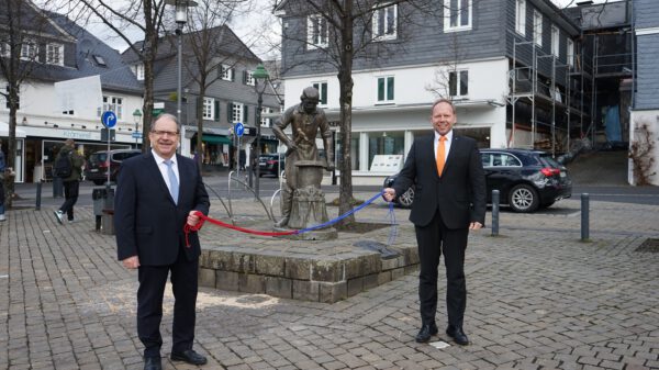 Zwei Männer stehen auf dem Olper Marktplatz und halten ein Seil in den Händen